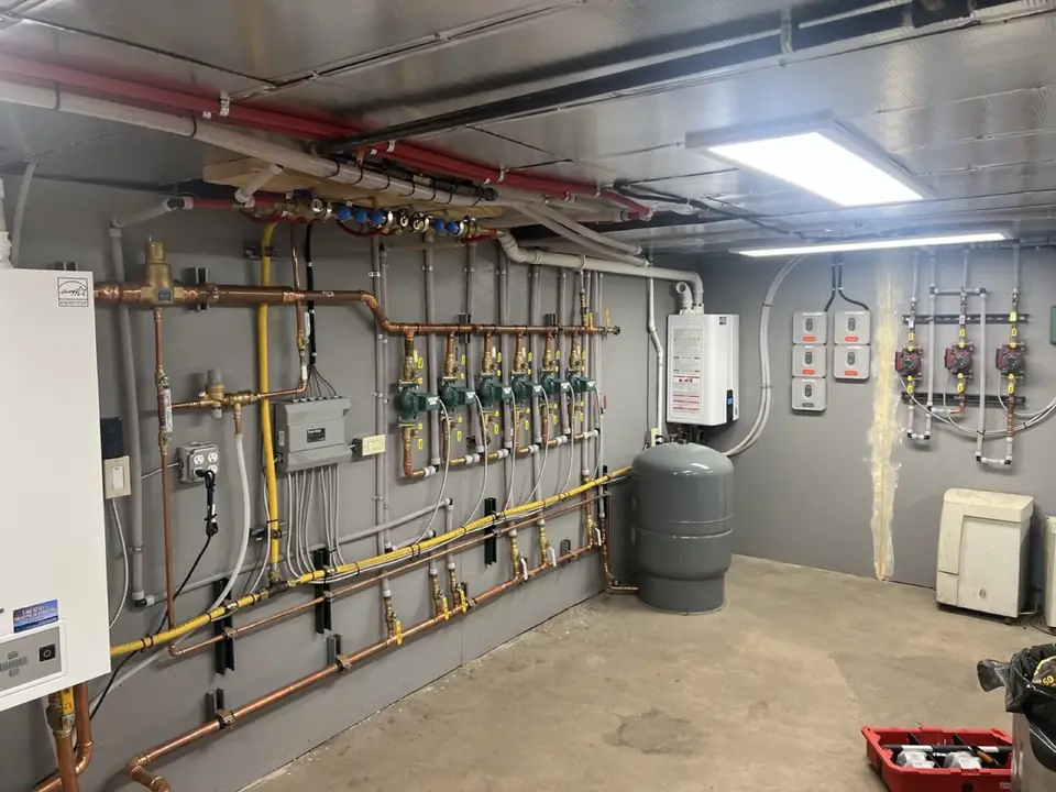 Copper heating manifold with green zone circulators and gas piping along a mechanical room wall