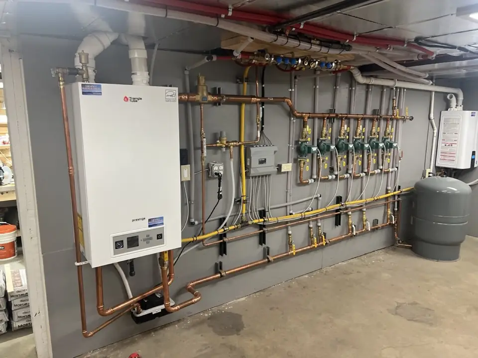 Wall-mounted Triangle Tube boiler with copper piping and a heating manifold