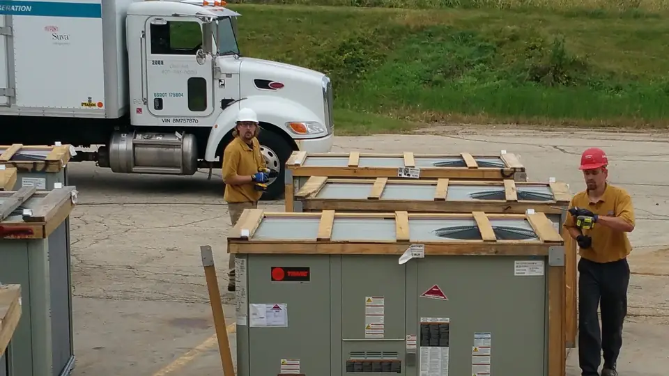 Crated rooftop HVAC equipment and crew at a delivery site